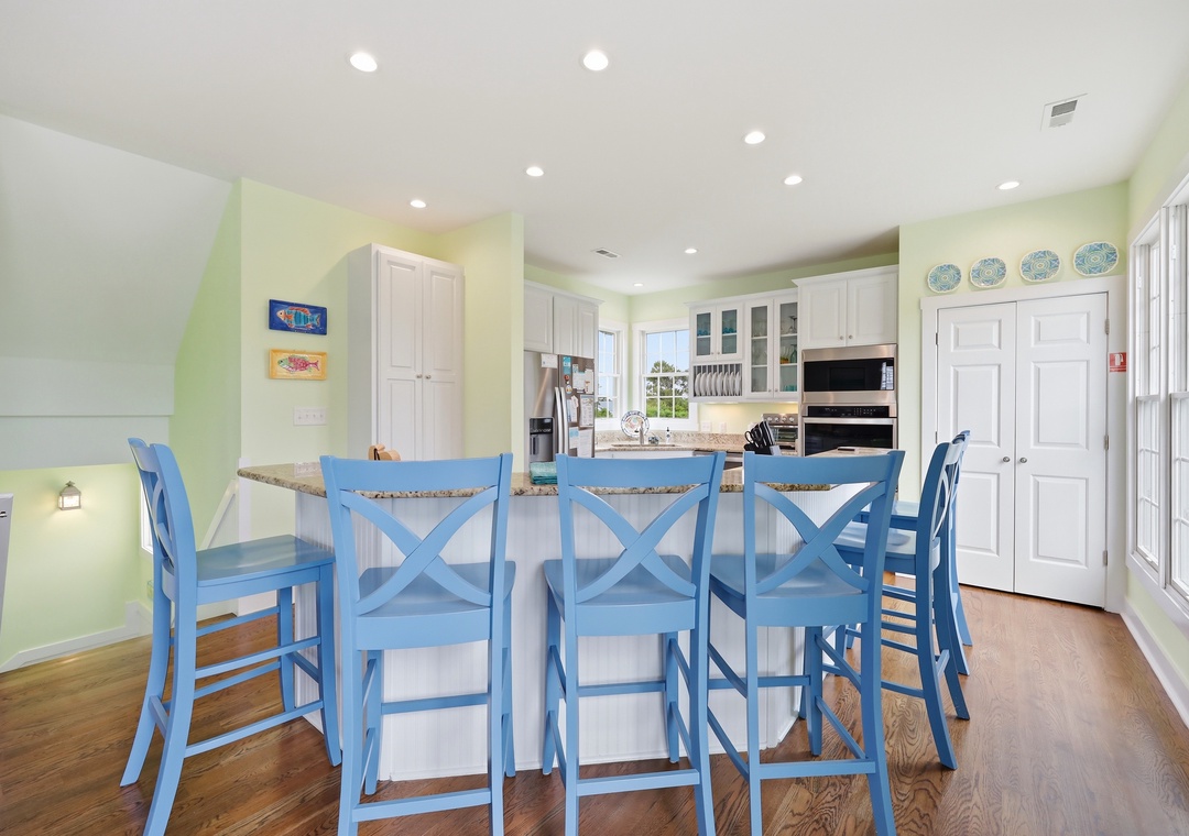 Picture yourself preparing meals at this spacious island, with room for everyone to gather on cheerful coastal blue stools. Bright natural light and a breezy palette make every moment feel like a vacation.