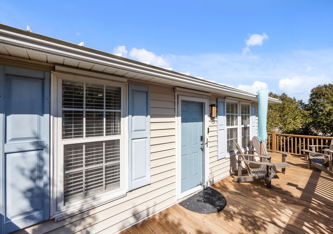Charming cottage exterior with spacious wooden deck and Adirondack chairs for relaxing in the sunshine.