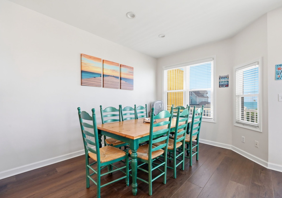 Gather around this inviting dining table with seating for eight, where sunlight and coastal breezes stream through large windows showcasing views of the surrounding area.