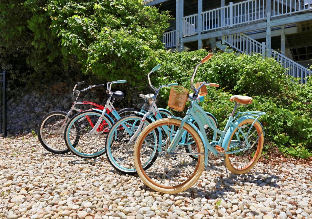 Colorful beach cruisers await on a pebbled path, perfect for exploring scenic coastal trails and nearby attractions during your stay.
