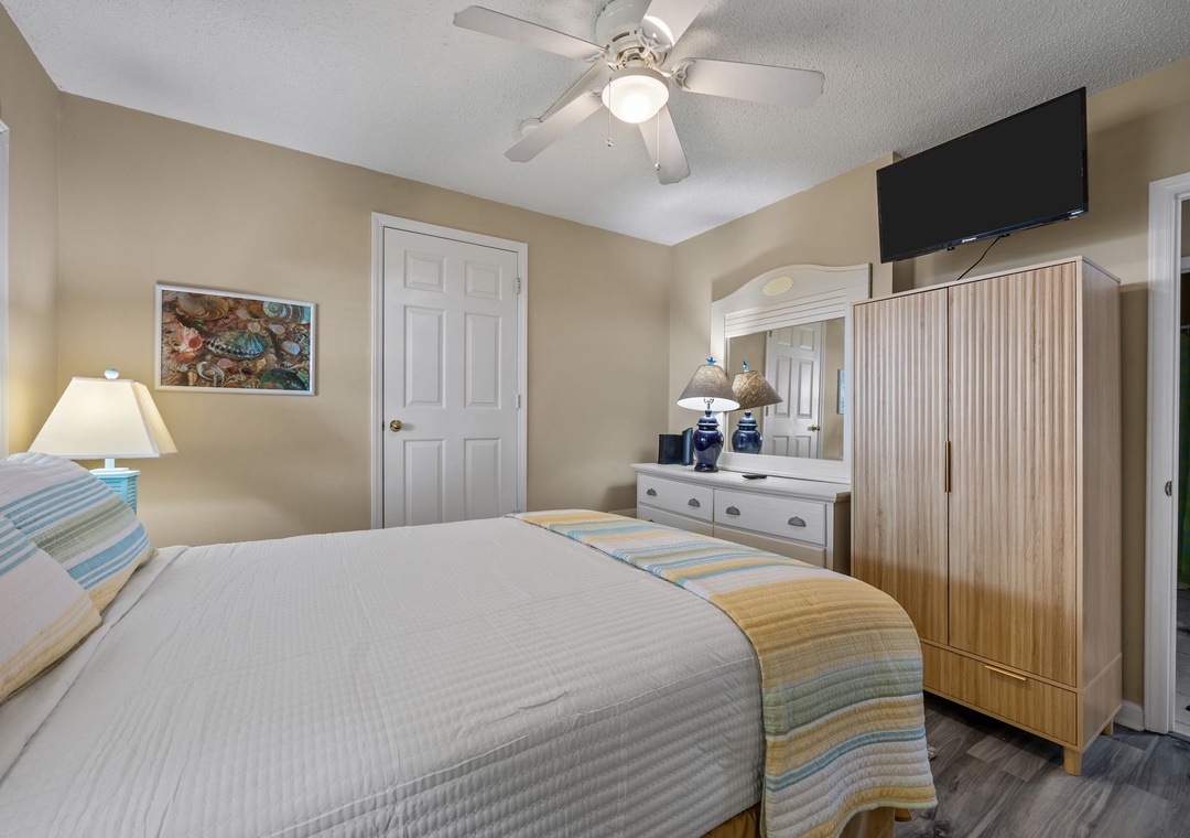 Unwind in your peaceful bedroom with a ceiling fan cooling you while watching TV on the wall-mounted screen.