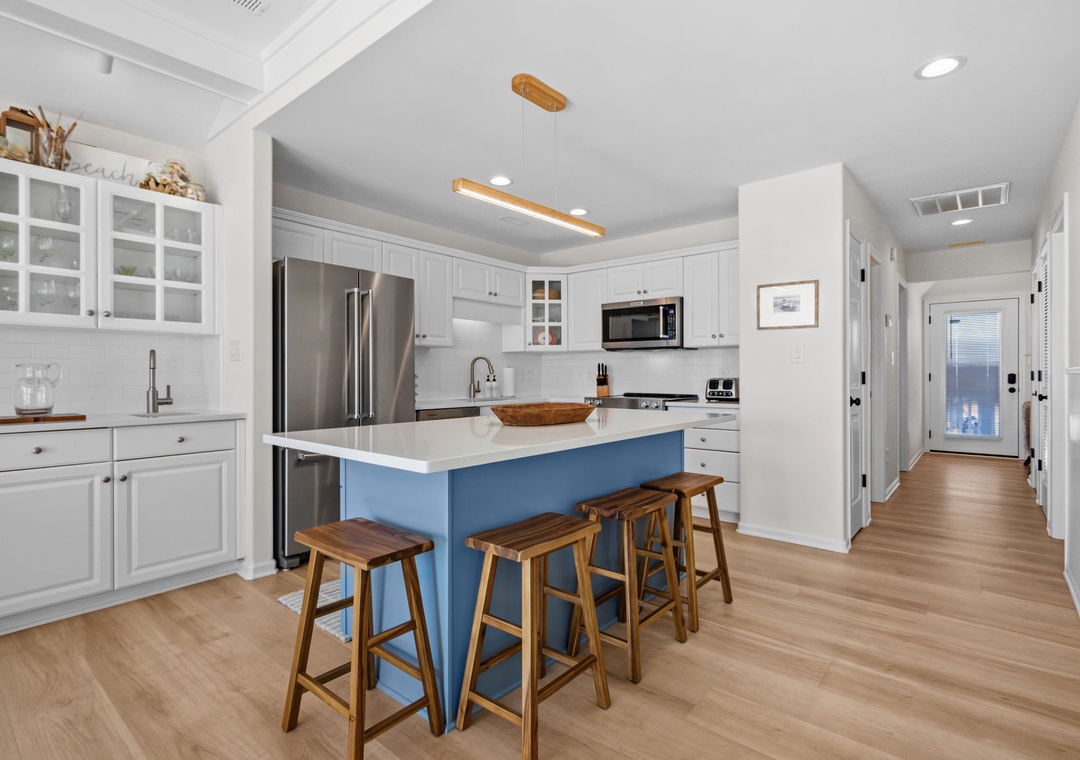 You'll love preparing meals in this bright, fully equipped kitchen with its spacious island and charming blue accents.