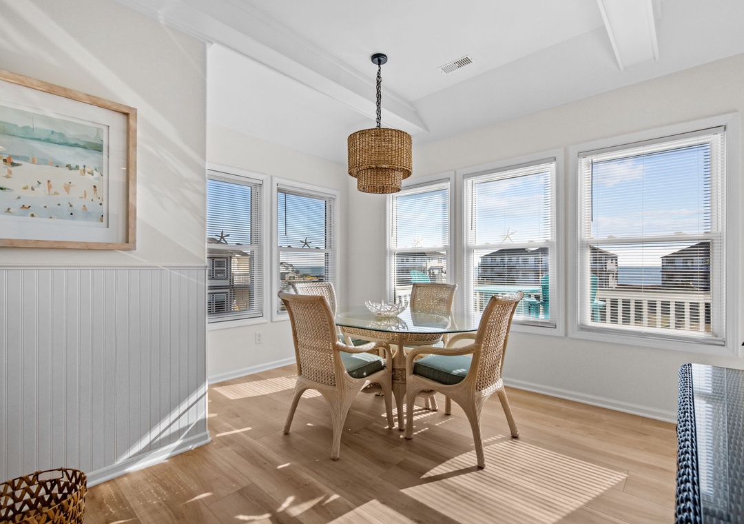 Share morning meals in your sunny dining nook, where natural wicker furnishings and ocean glimpses create a serene coastal breakfast spot.