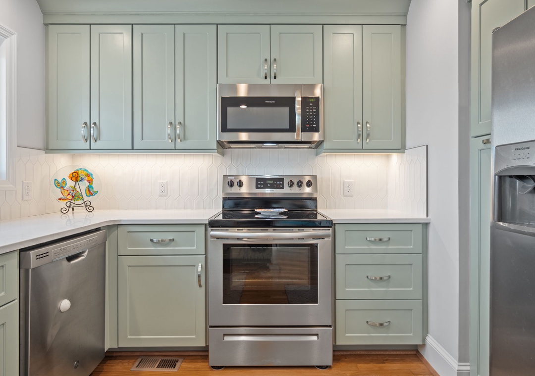 Step into your fully-equipped kitchen with sage-green cabinets, stainless steel appliances, and charming details that make cooking feel like home.