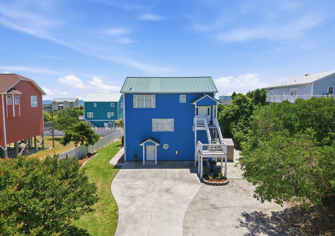A bright blue coastal home nestled in a quiet residential area, offering easy beach access and a welcoming neighborhood atmosphere.
