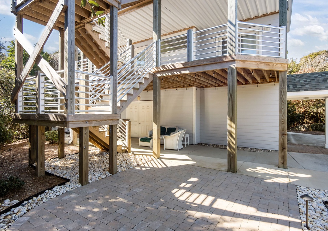 Your private patio features elegant stone pavers beneath a multi-level deck structure, creating perfect spaces for outdoor dining and relaxation.
