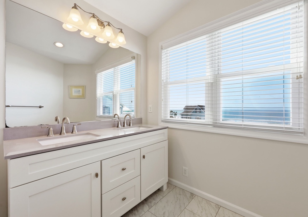 Freshen up in your bright coastal bathroom with dual sinks, stylish fixtures, and serene sea views right from your window.
