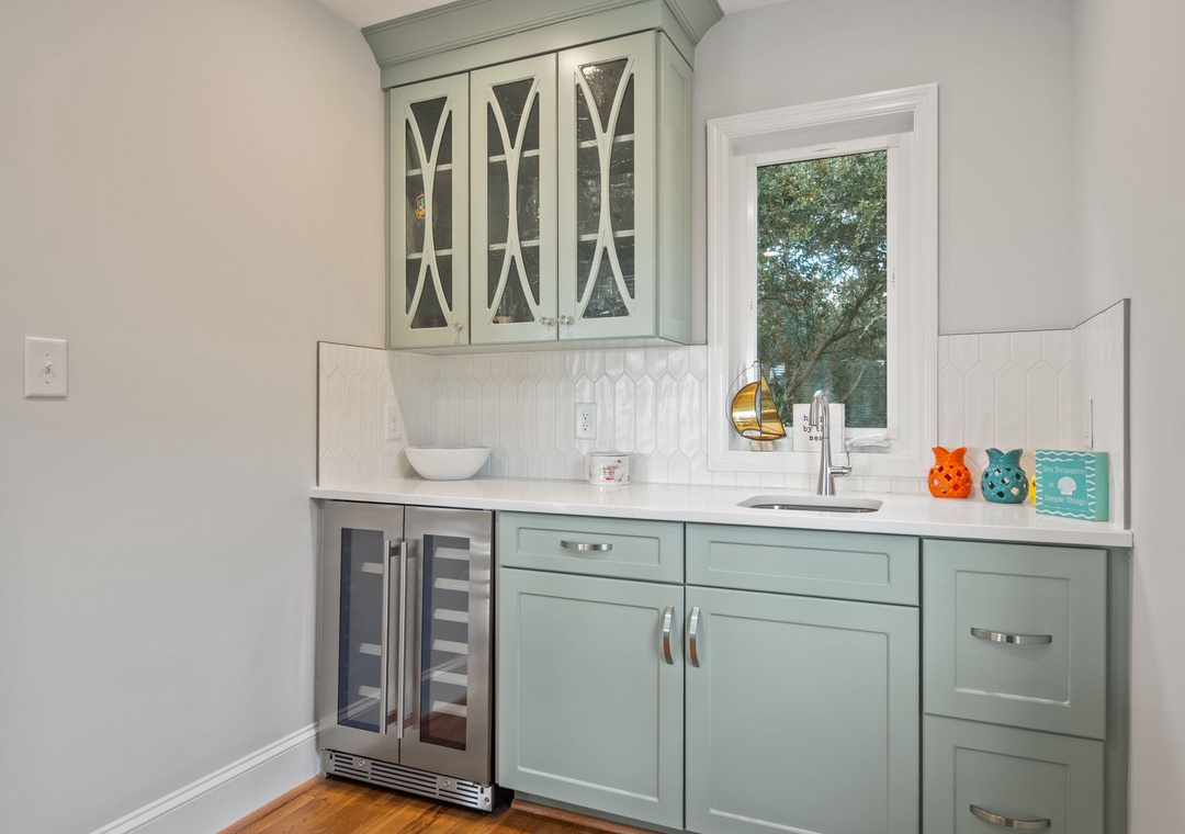 Your charming wet bar features elegant sage-green cabinets and marble countertops, perfect for morning coffee or evening wine.