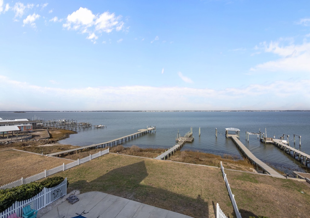 Waterfront property overlooking calm bay waters with multiple private docks and piers extending into the peaceful harbor area.