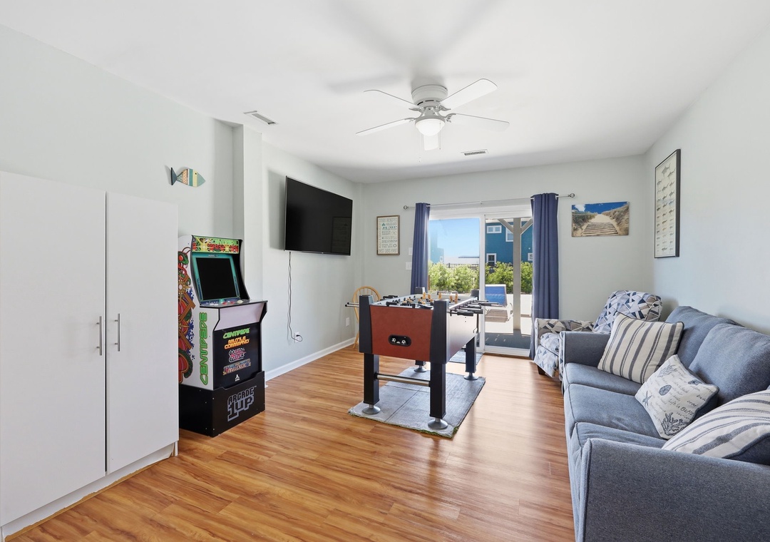 Your bright, coastal living room invites you to unwind with arcade games, foosball fun, and relaxing ocean views just beyond the door—perfect for laid-back vacation days.