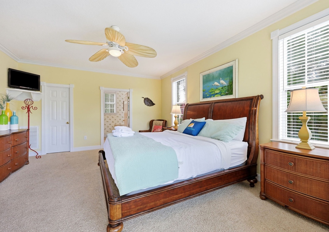 Your coastal-inspired bedroom awaits with plush bedding, soothing yellow walls, and tropical ceiling fan. Unwind in this serene retreat designed for restful nights and relaxed mornings.