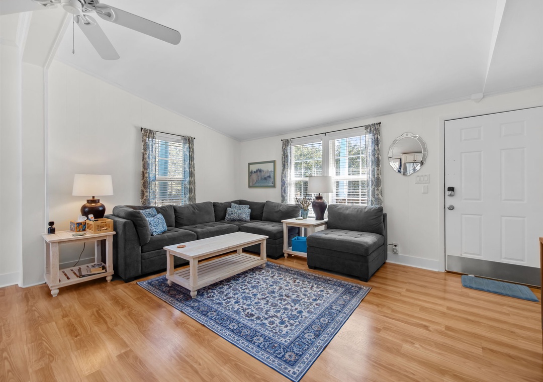 Unwind on the plush sectional sofa in your bright, airy living room featuring gleaming hardwood floors and charming coastal decor.