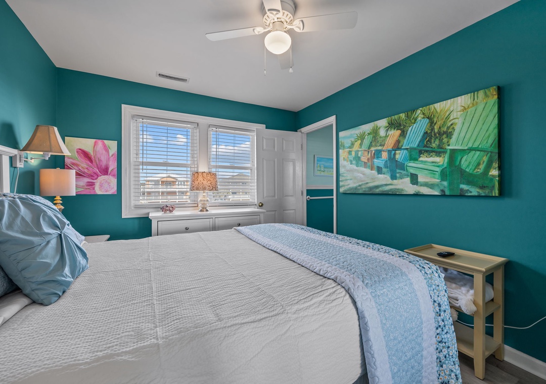 Drift into coastal dreams in this vibrant bedroom with turquoise walls and tropical artwork creating your perfect seaside retreat.