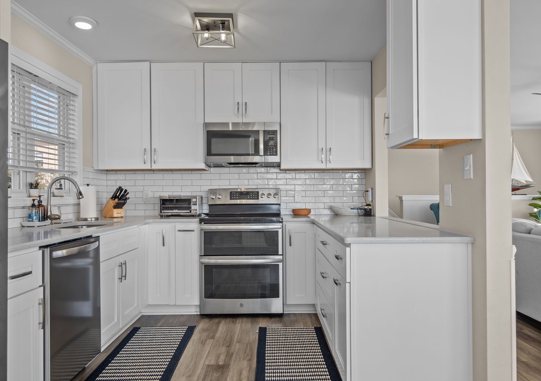 Your fully equipped kitchen awaits with pristine white cabinets, stainless steel appliances, and gleaming countertops for effortless meal preparation.