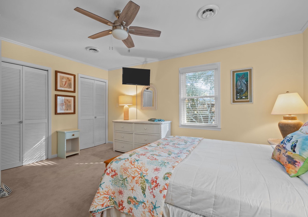 Drift off in your peaceful bedroom featuring a ceiling fan, flat-screen TV, and soft natural light from your window.