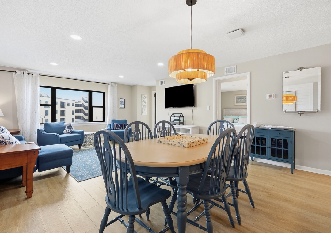 Gather around the spacious dining table with seating for eight, where natural light streams in and inviting blue armchairs beckon you to unwind in the open-concept living area.