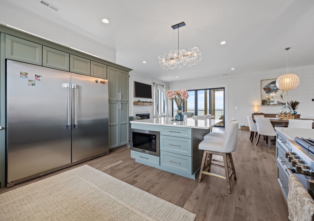 Your gourmet kitchen invites culinary adventures with gleaming appliances, elegant island seating, and sparkling chandeliers creating the perfect gathering space.