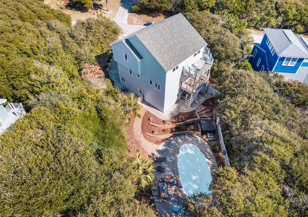 Aerial view of vacation rental property featuring private pool surrounded by lush coastal vegetation and natural landscape.