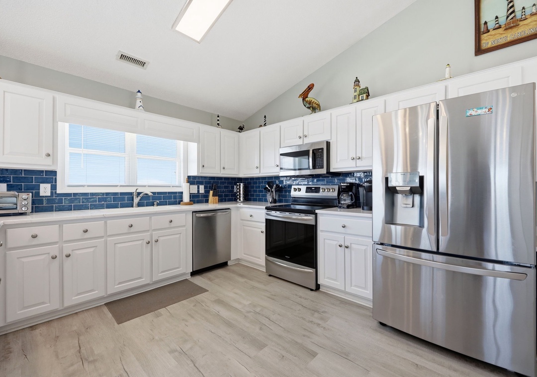 Your spacious kitchen features crisp white cabinetry, stainless steel appliances, and a bright blue tile backsplash that adds a coastal charm. Natural light from skylights makes meal prep a joy.