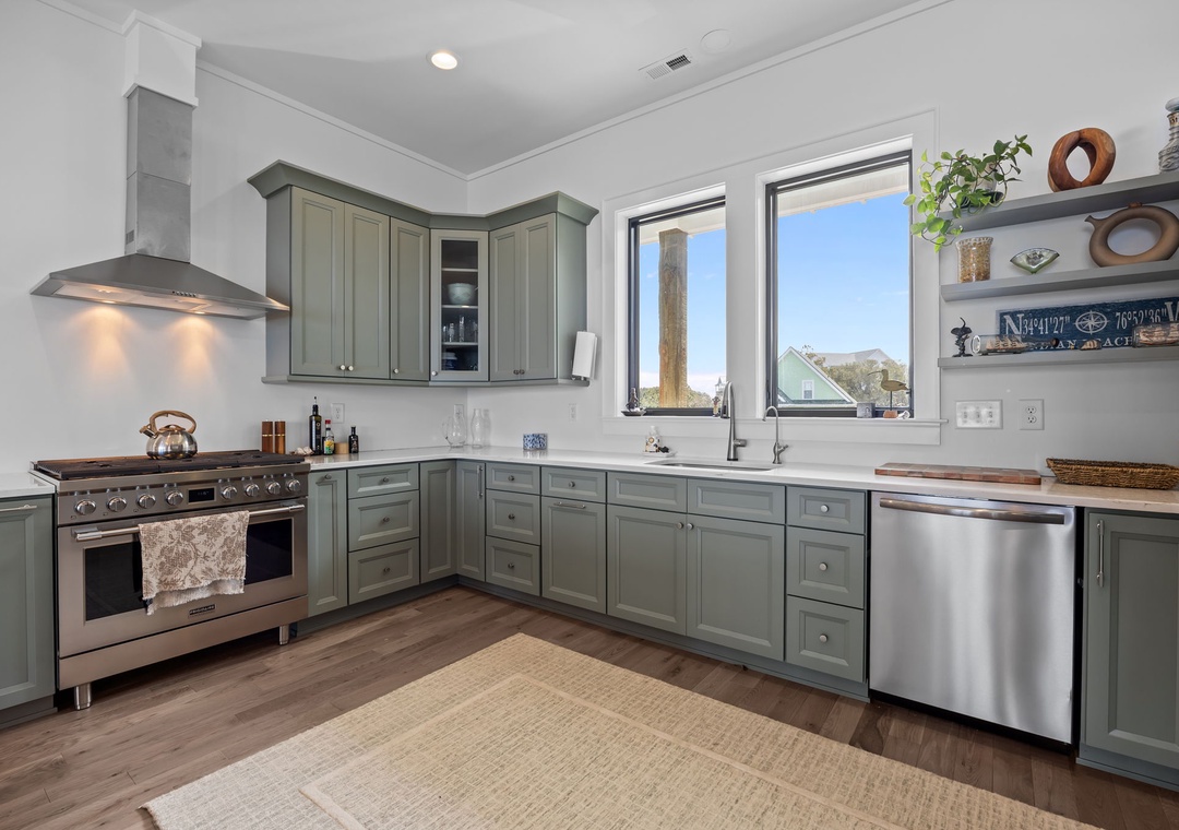 Your fully-equipped kitchen features sage green cabinets, stainless appliances, and windows that fill the space with natural light as you prepare meals.