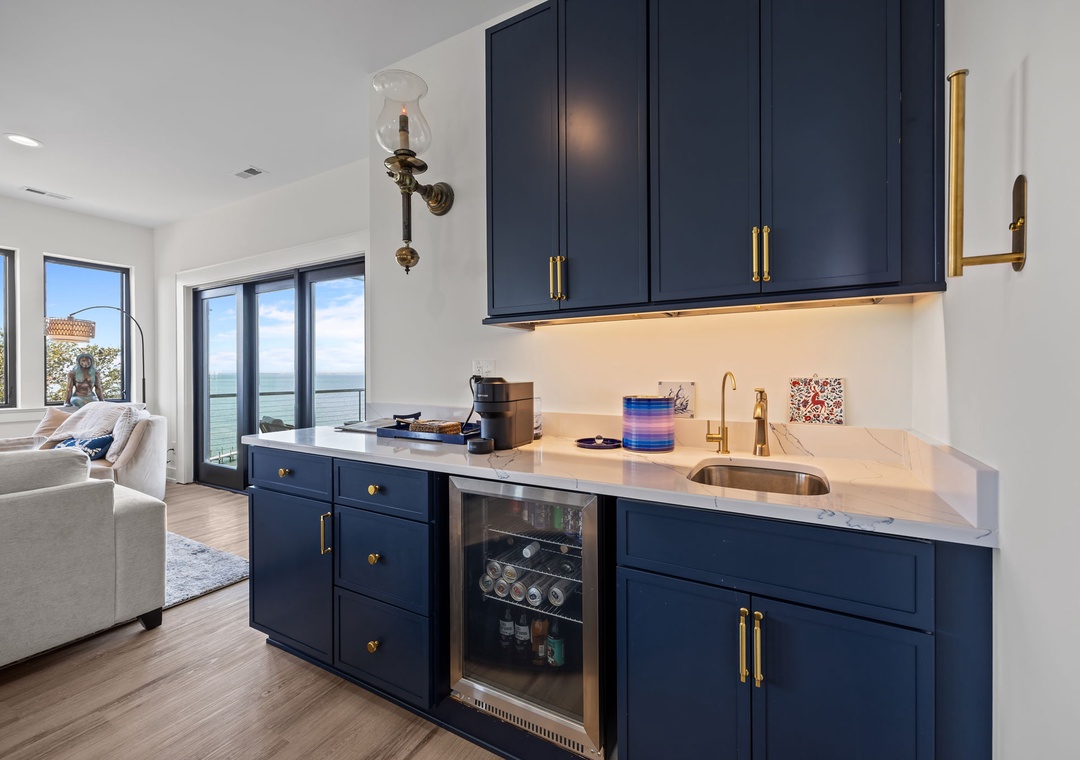 Your stylish kitchenette features elegant navy cabinetry, gleaming countertops, and stunning water views that create the perfect backdrop for memorable vacation meals.