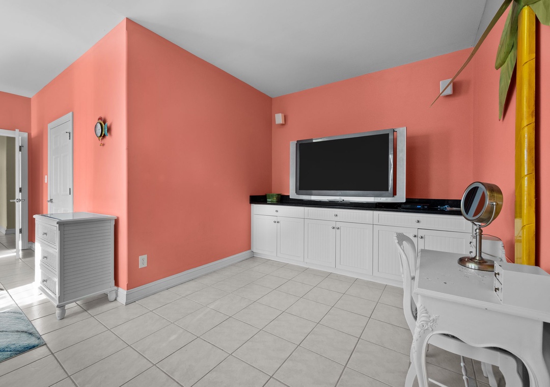 Relax in your vibrant living space where coral walls create warmth and white furnishings offer comfort for movie nights and peaceful moments.