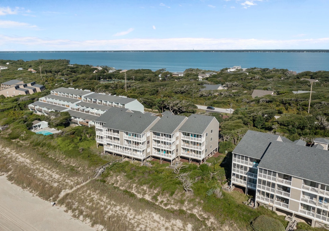 Beachfront resort buildings nestled among coastal vegetation with direct ocean access and scenic dune landscapes.
