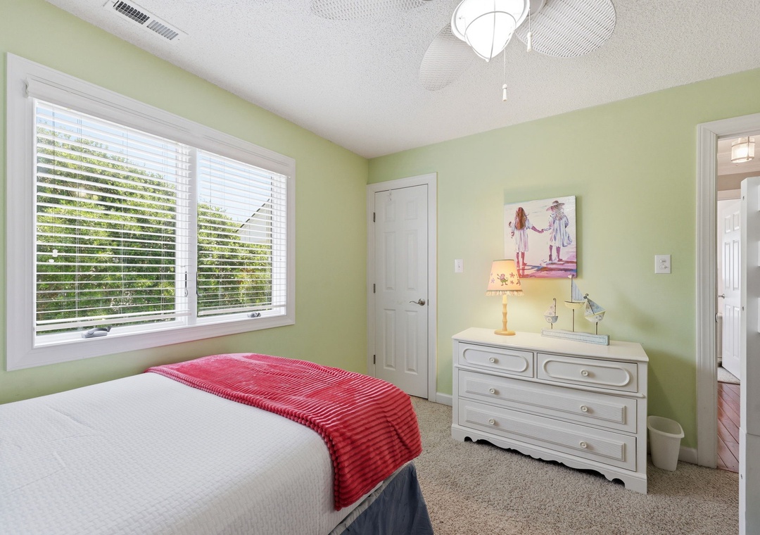 Settle into this bright, cheerful bedroom where soft green walls and natural light create a calm, restful retreat for your getaway.
