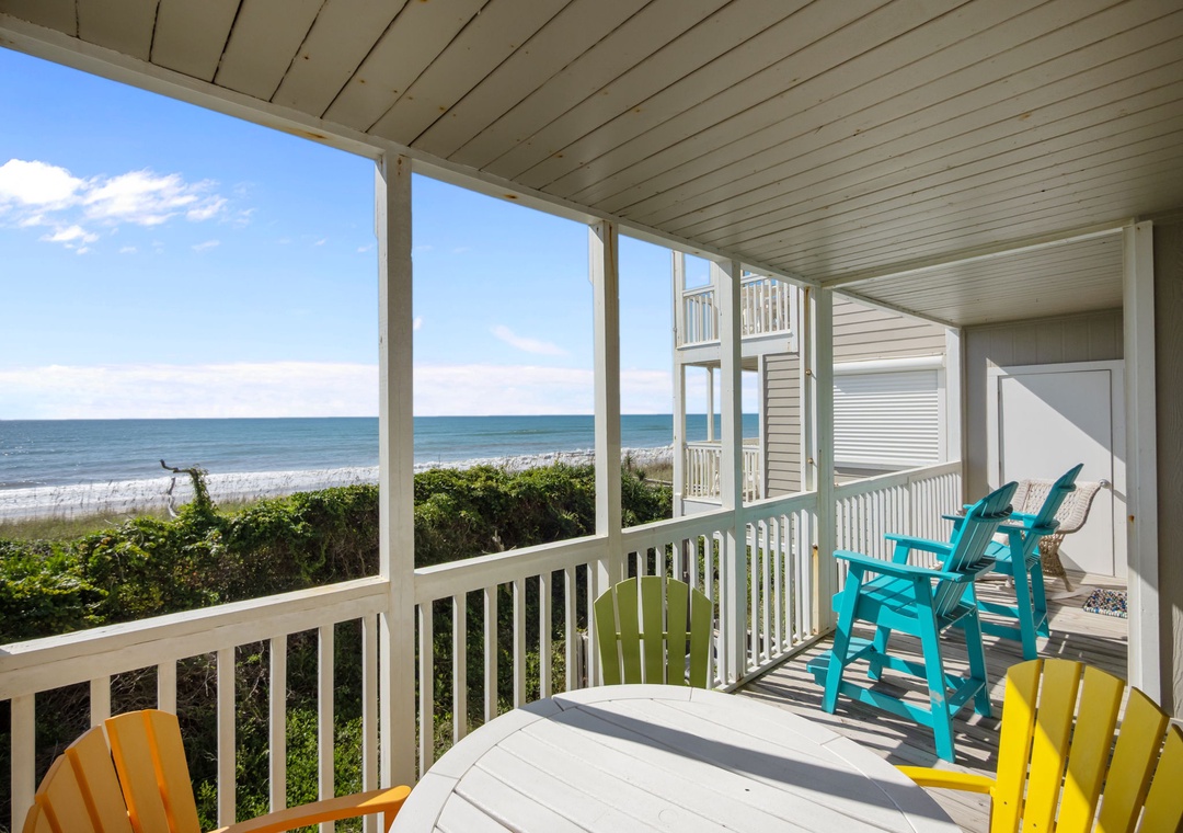 Covered porch with colorful beachfront seating and direct ocean views for your perfect coastal getaway.