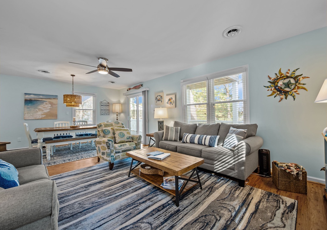 Your bright, coastal-inspired living space welcomes you with soft blues, comfortable seating, and natural light streaming through large windows.