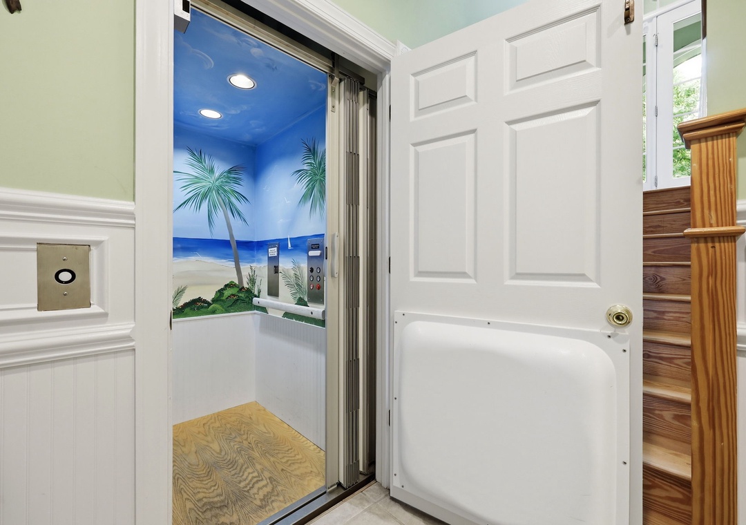 A residential elevator with beach-themed tropical mural offers convenient accessibility between floors in this coastal vacation home.