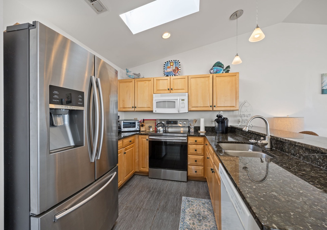 Your fully equipped kitchen features stainless steel appliances and granite counters, perfect for preparing meals with natural light streaming through the skylight.