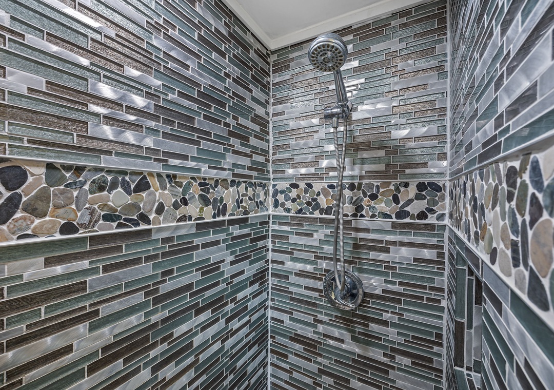 Step into your beautifully tiled shower featuring stunning glass mosaic walls and natural stone accents that create a spa-like retreat.