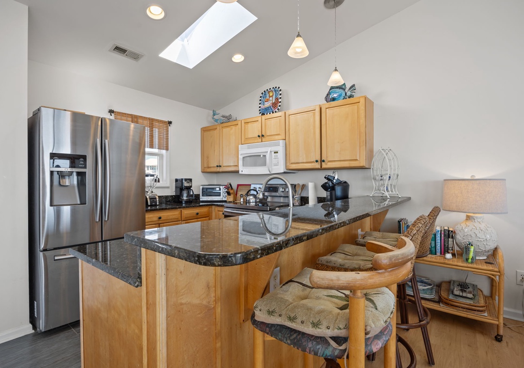 Your bright, fully-equipped kitchen invites culinary adventures with granite countertops, stainless steel appliances, and a sunny skylight overhead.