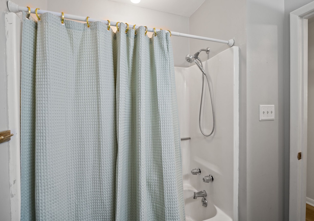 Step into your private bathroom featuring a spacious tub-shower combo with refreshing rainfall showerhead and soft spa-like curtain for ultimate relaxation.