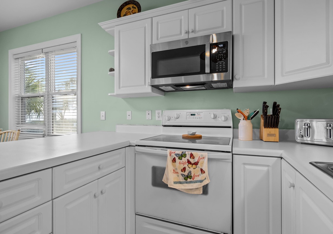 Your fully equipped kitchen features crisp white cabinets, stainless appliances, and soothing mint walls—perfect for preparing morning coffee or home-cooked meals.