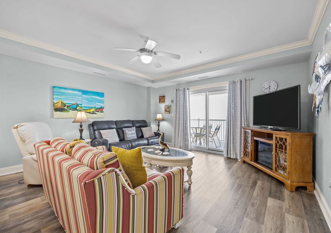 Relax in your bright living room featuring coastal artwork, comfy seating, and a balcony with scenic views.