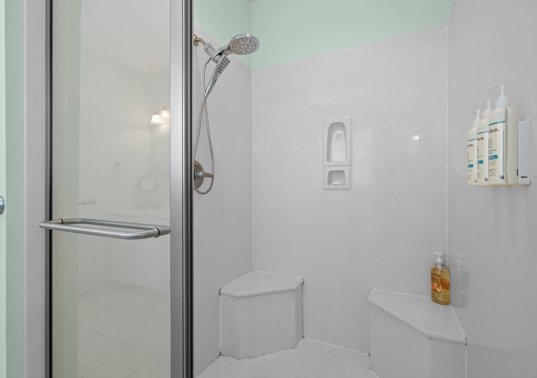 Step into your pristine shower with modern fixtures and convenient corner seating for ultimate relaxation.