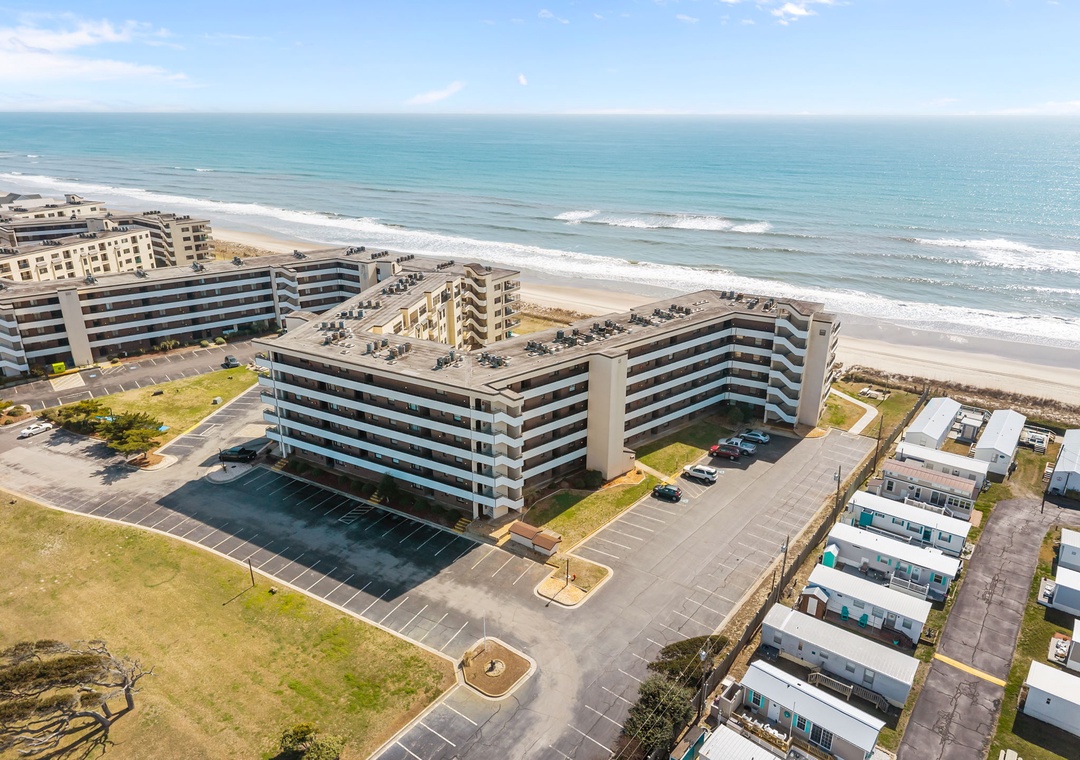 Beachfront property positioned directly along pristine sandy shores, featuring modern multi-story buildings with convenient parking and easy beach access in a tranquil coastal setting.