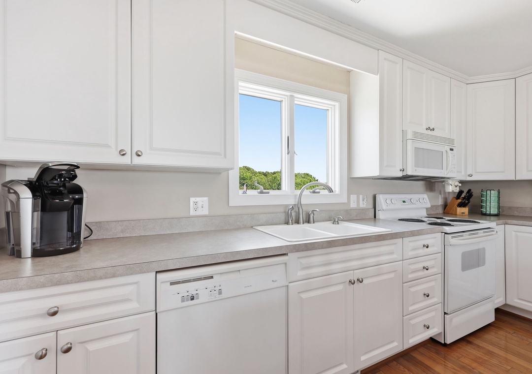 Bright, all-white kitchen with modern appliances, ample counter space, and natural light. Equipped with a coffee maker and everything you need for easy meal prep during your stay.