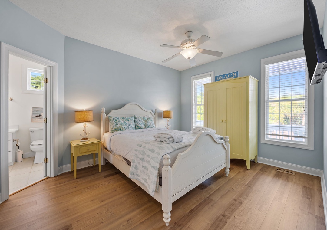 Drift off in your serene coastal bedroom featuring soft blue walls, gleaming hardwood floors, and charming beachy touches throughout.