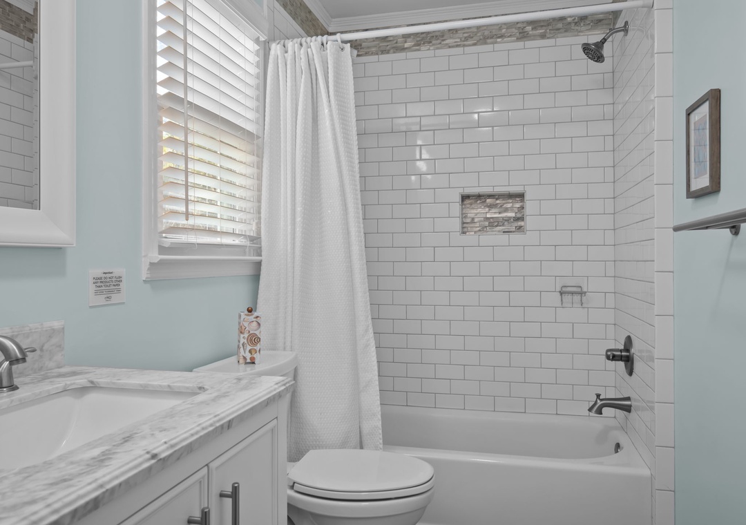 Refresh in your pristine bathroom with a luxurious tub-shower combo, elegant subway tiles, and soothing mint-green walls that create a spa-like retreat.