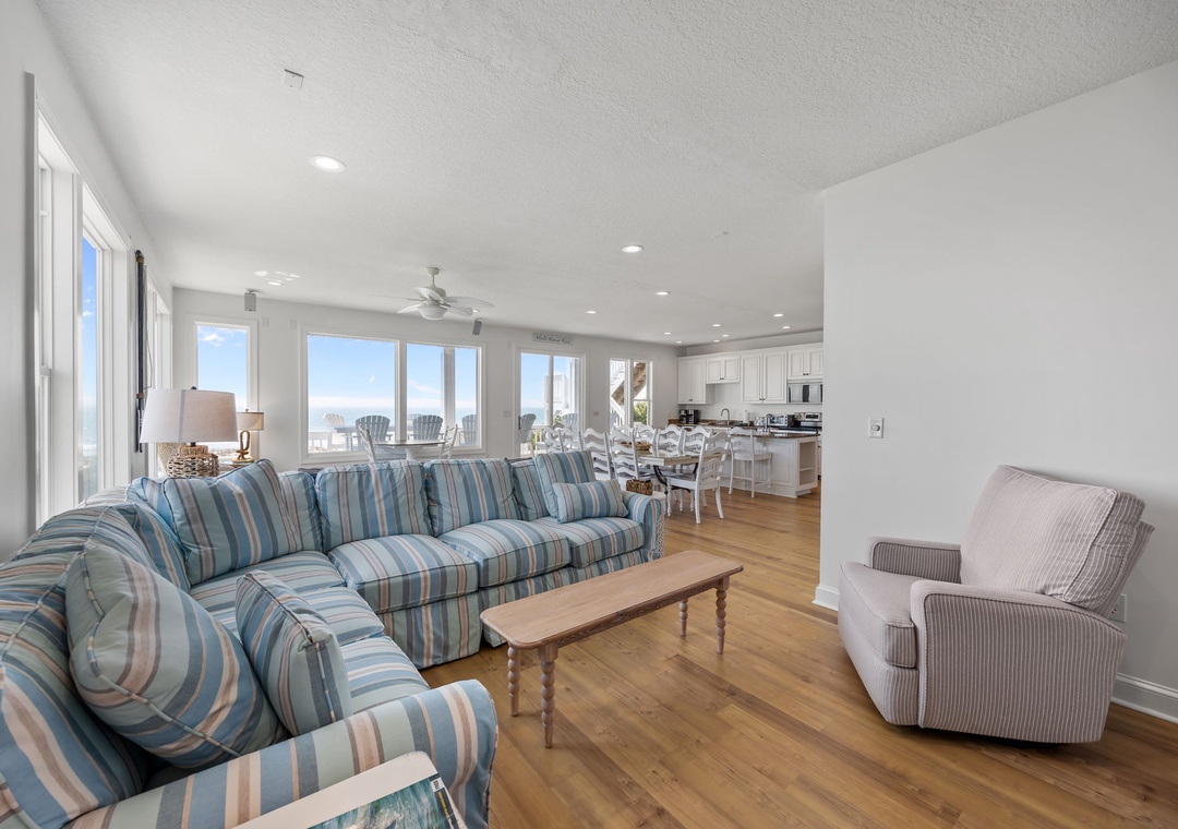 Relax in your bright, airy living space with coastal-striped seating and panoramic windows that fill the room with natural light and ocean views.