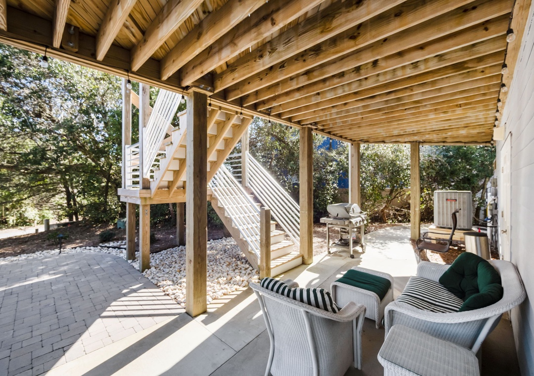 Relax in your private covered patio with comfortable wicker seating and BBQ access, perfect for peaceful outdoor moments.