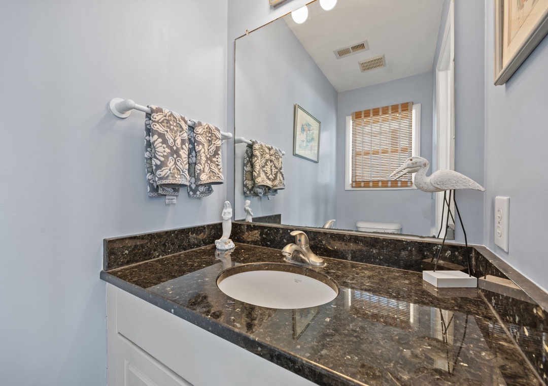 You'll feel refreshed in this elegant bathroom featuring granite countertops, decorative towels, and coastal touches.