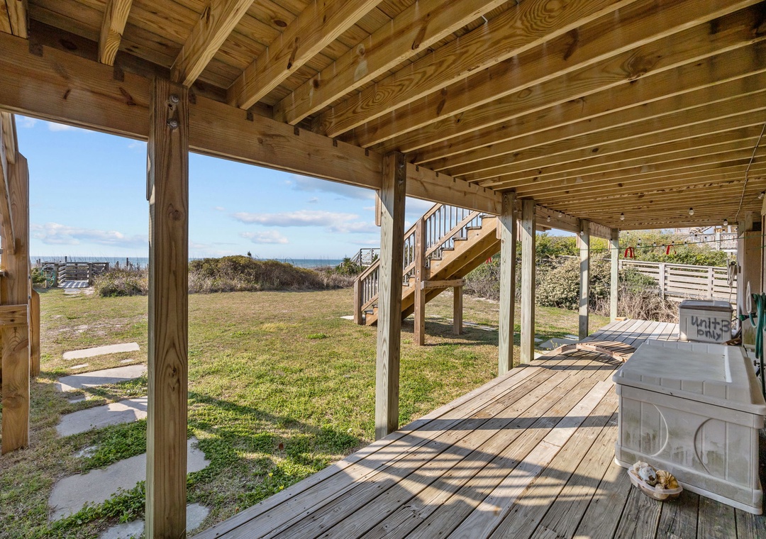 Your covered deck opens to ocean views and beach access, with warm wooden beams creating the perfect coastal retreat.