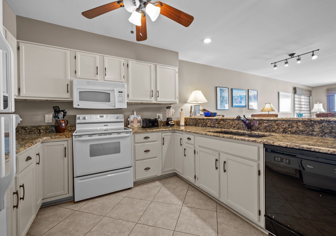 Your fully equipped kitchen features granite countertops, white appliances, and ample cabinet space for preparing memorable vacation meals.