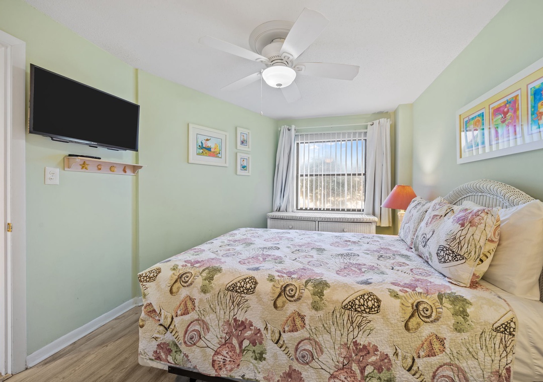 Relax in your coastal bedroom featuring cheerful green walls, seashell-themed bedding, and a ceiling fan for comfort.