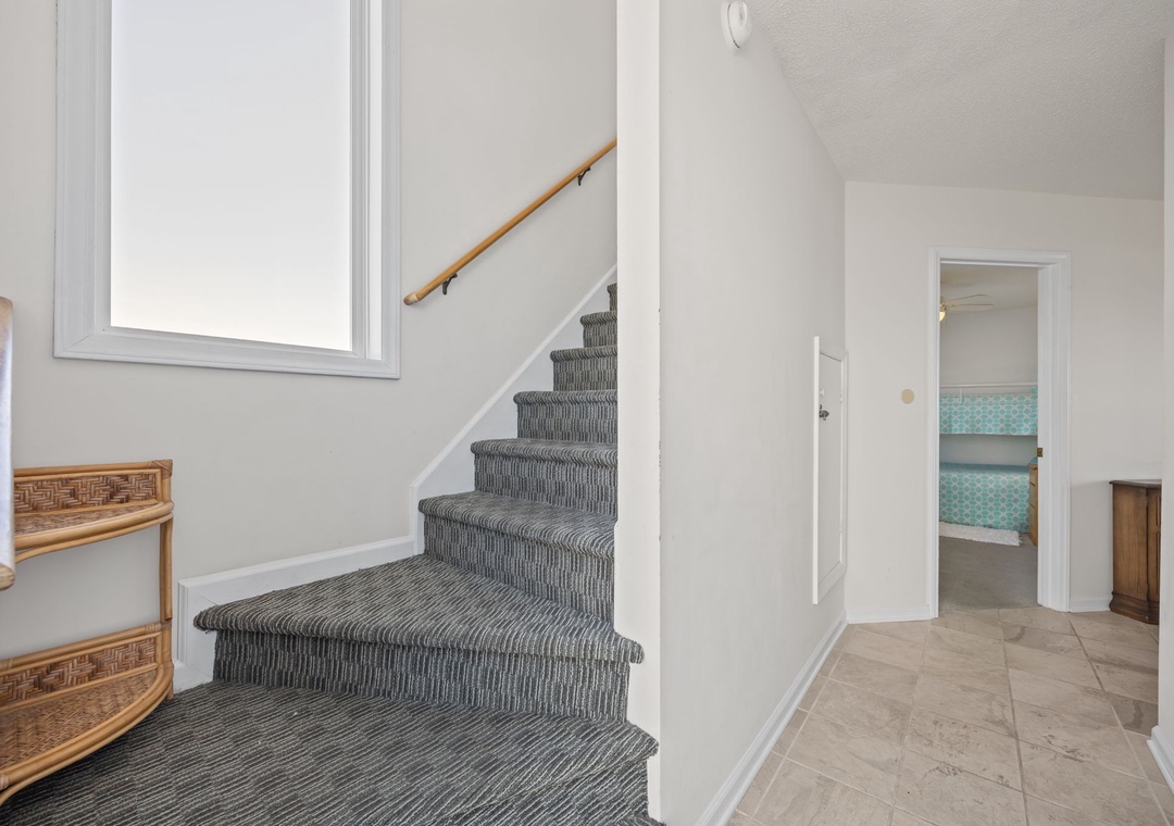 Step into your bright, welcoming entryway where natural light fills the space and carpeted stairs lead to your upstairs retreat.