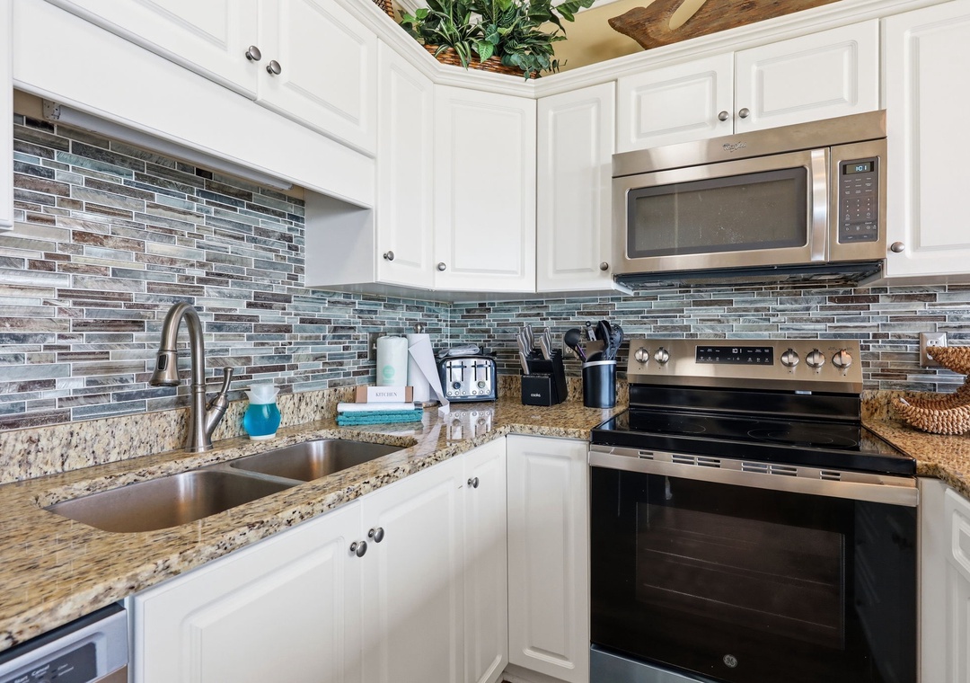 Step into a fully equipped kitchen with stainless steel appliances, granite countertops, and a stylish glass tile backsplash—your home away from home for preparing vacation meals.